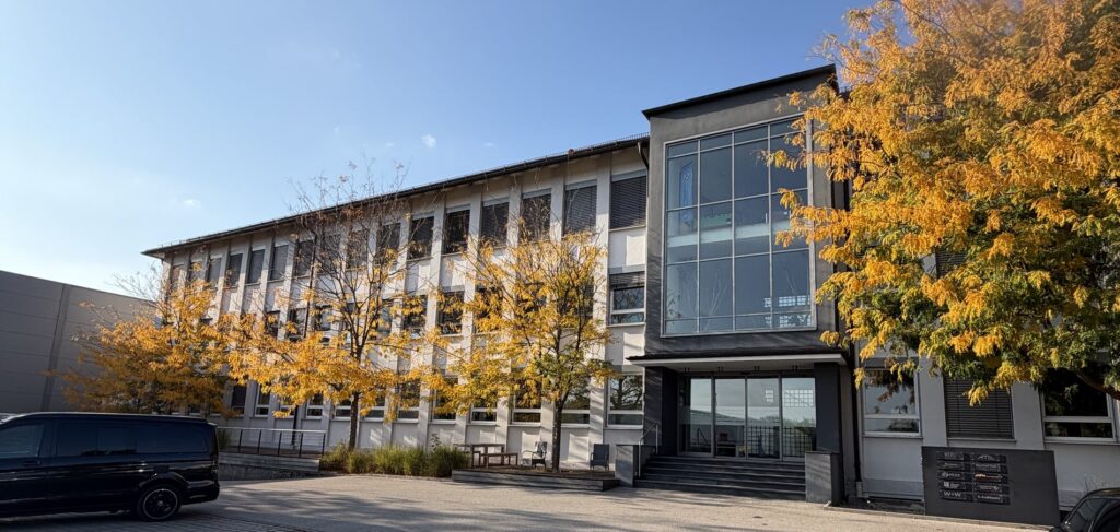 Das WEKU-Bürogebäude mit Glasfront und herbstlich gefärbten Bäumen davor