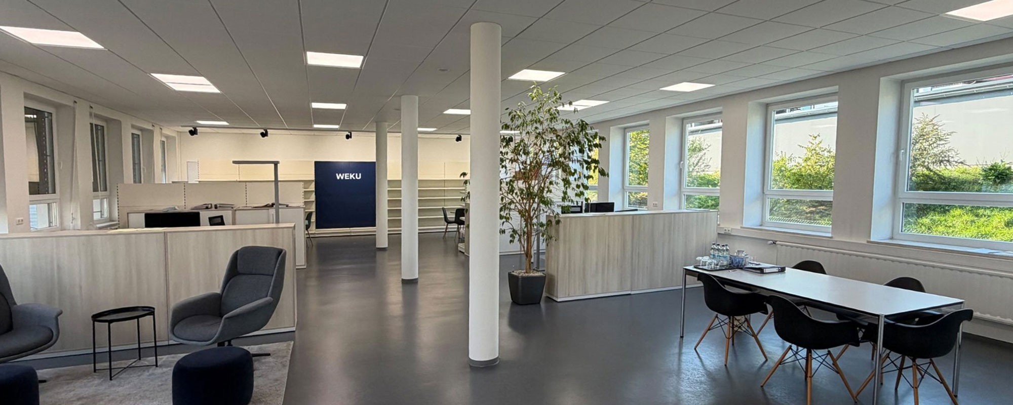 Offener Bürobereich bei WEKU mit Sitzecke, Besprechungstisch und Fensterfront