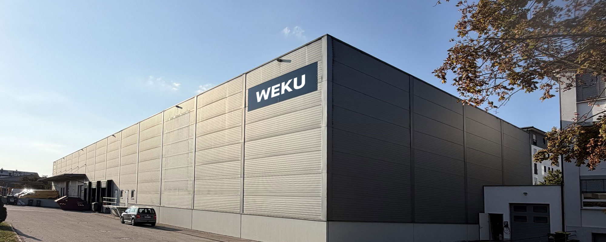 Aussenansicht der WEKU-Lagerhalle mit Firmenschild und Zufahrtsstrasse